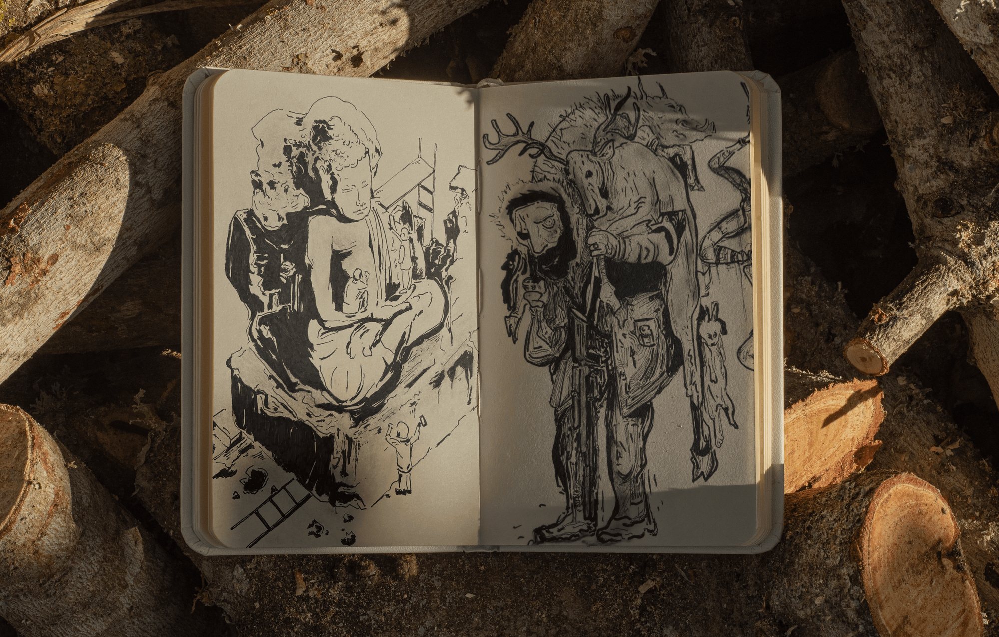 Open sketchbook with two ink drawings of figures, resting on logs